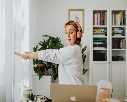 Woman stretching at her home office desk by the window
